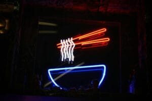 a neon sign with a bowl of noodles and chopsticks