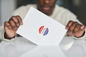 person putting a paper in white ballot box