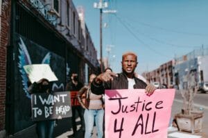 man in black jacket holding white and pink banner